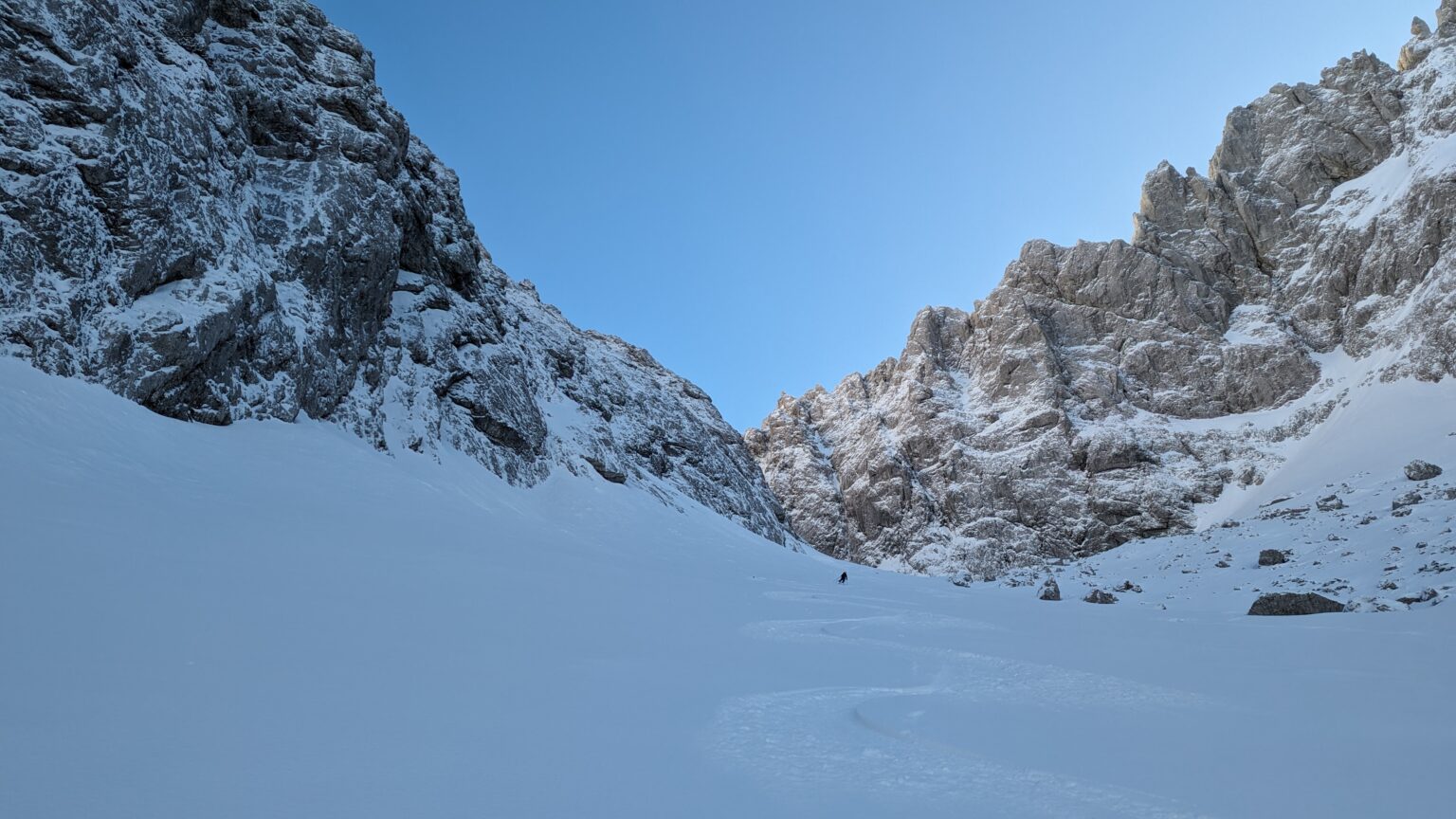 Abfahrt durch eine verschneite Rinne zwischen den Felswänden des Wilden Kaisers