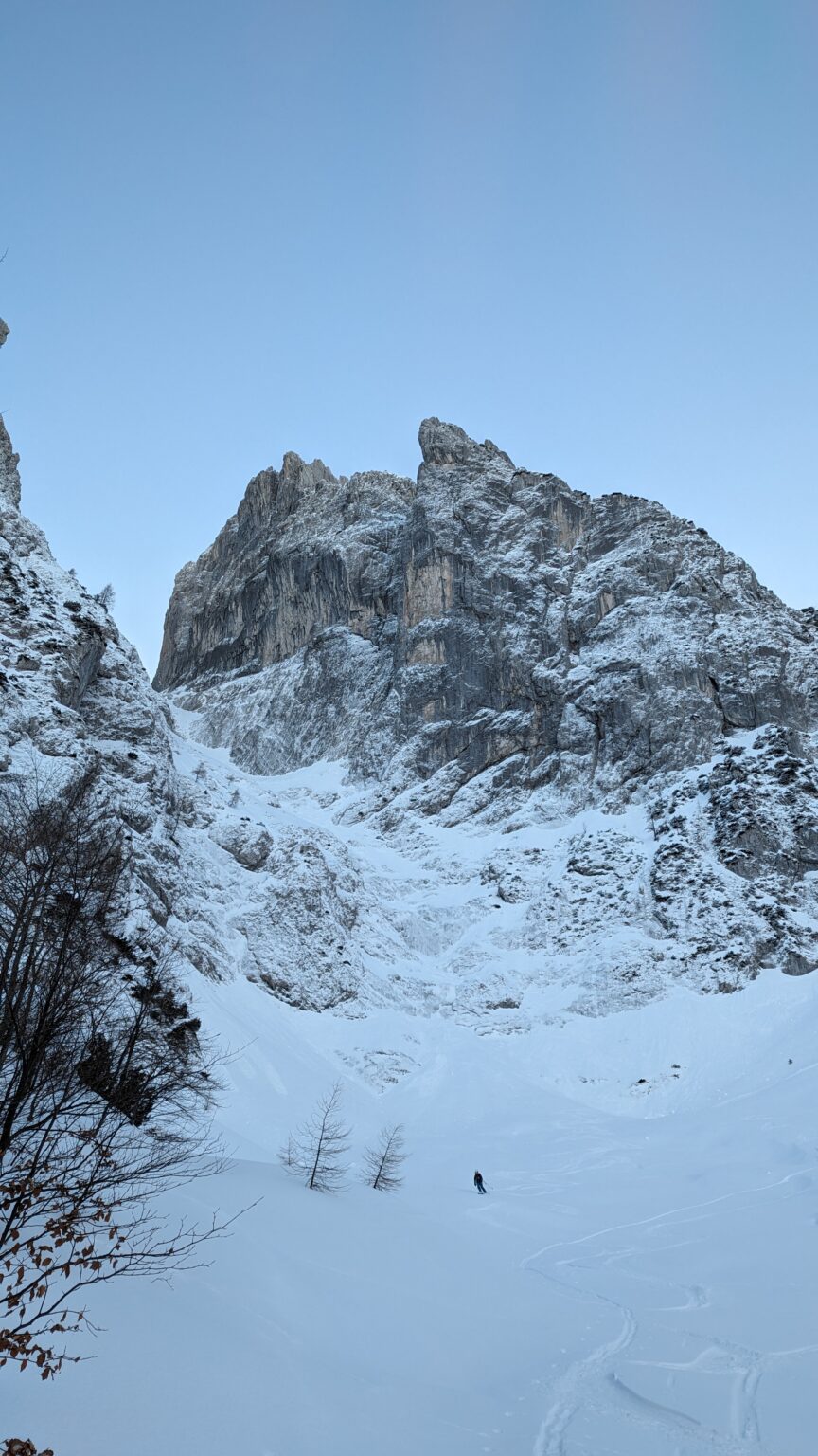 Skibergsteiger in einem verschneiten Kar unter einem Felsgipfel im Wilden Kaiser